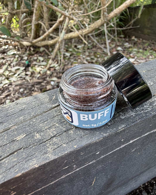 An open jar of Trail Armour BUFF lip scrub with the lid beside it, showing the sugar scrub inside