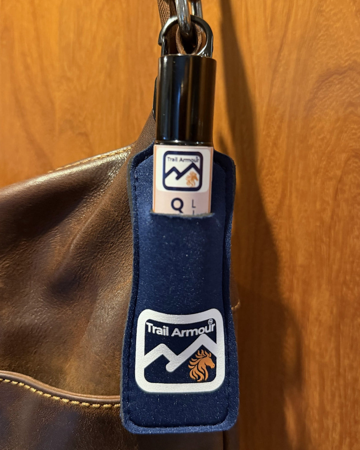 Trail Armour QUENCH lip balm roller sitting in a navy neoprene holder clipped to a bag