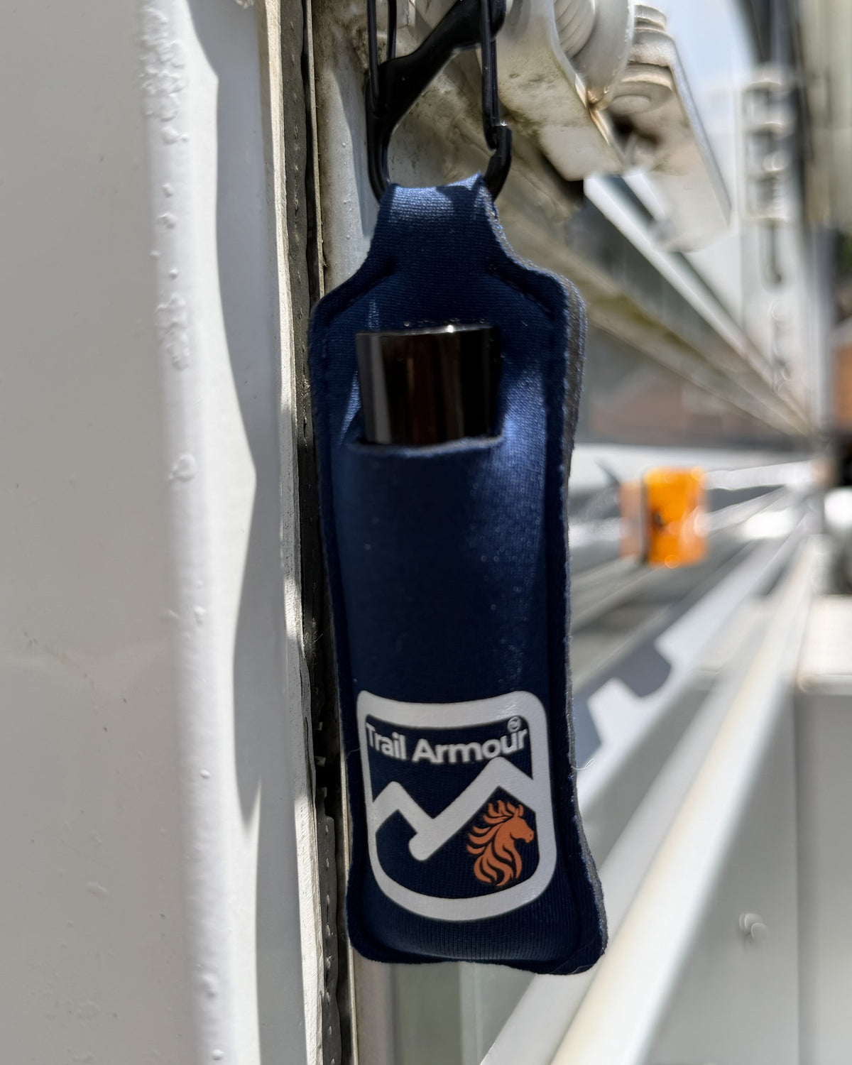 Navy neoprene Trail Armour lip balm holder holding a lip balm tube, clipped to a rail