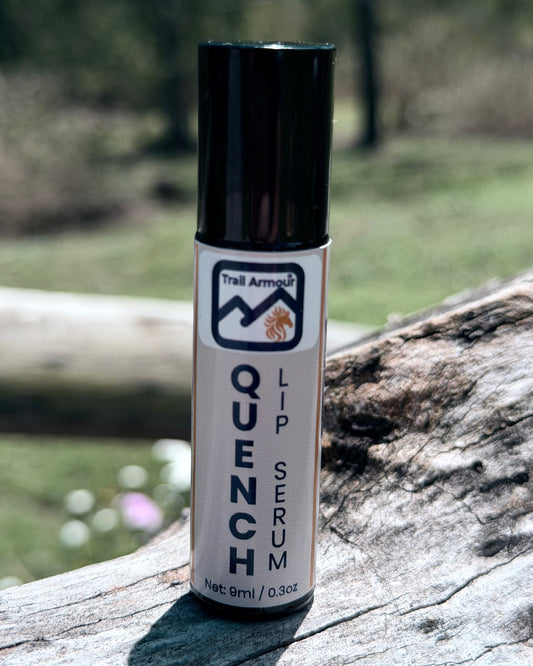 Trail Armour QUENCH hydrating lip serum roller standing against tree bark