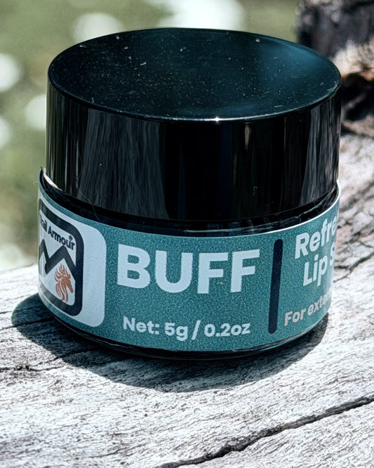 Trail Armour BUFF lip scrub jar resting against tree bark