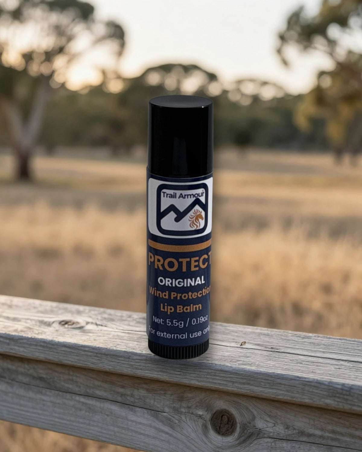 A tube of Trail Armour PROTECT wind and weather lip balm on a weathered wooden fence